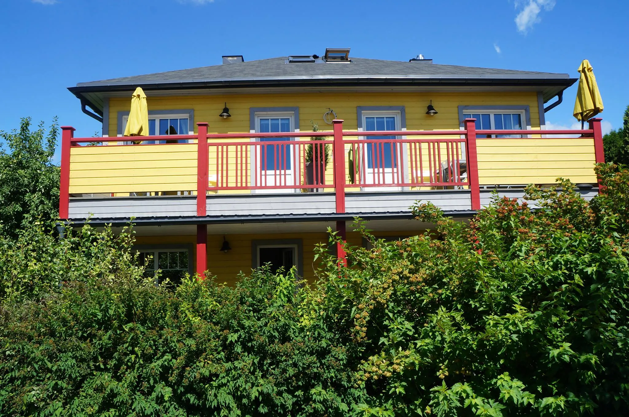 Mr Fox guest house with red balconies and its green garden in summer
